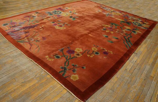 Lustrous rust rug with yellow and green floral branches displayed on worn plank hardwood floors.