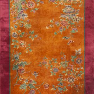 Orange rug with multicolor stylized floral designs and a wide, solid magenta border.