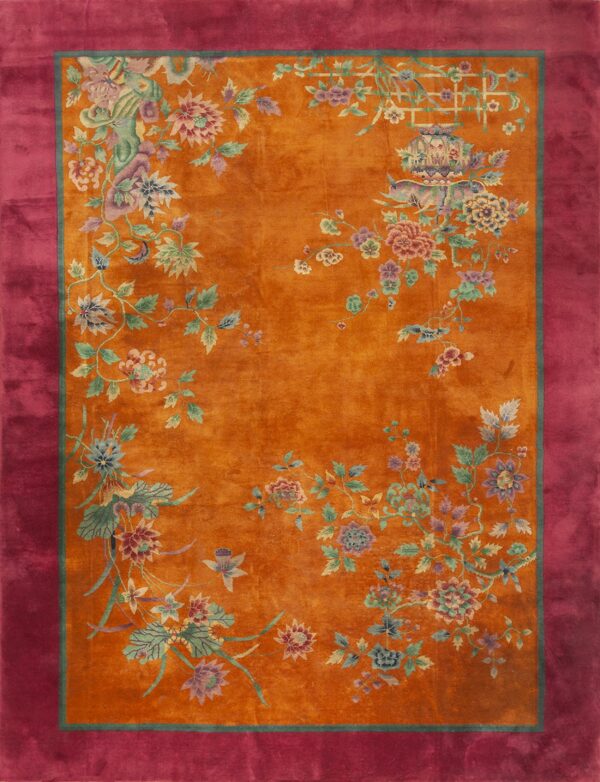 Orange rug with multicolor stylized floral designs and a wide, solid magenta border.