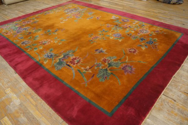 Plush orange rug with scattered pastel floral motifs and a wide red border on rustic wooden planks.