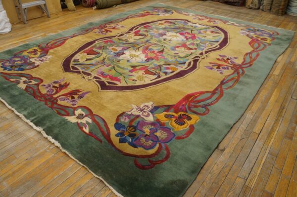 Gold rug featuring a multicolored floral medallion, sage green border, and lying on wooden floorboards.