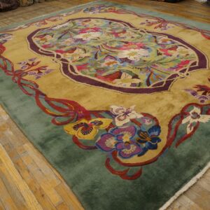 Plush golden Art Nouveau rug with vibrant floral designs and a sage border on worn wood floors.
