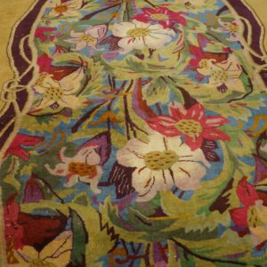 Sculpted pile rug displaying stylized flowers and foliage in gold, teal, pink, and purple colors.