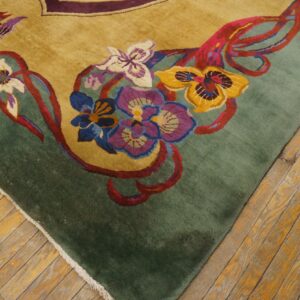 A high-pile rug with colorful floral motifs on a gold and green field rests on distressed wooden floors.