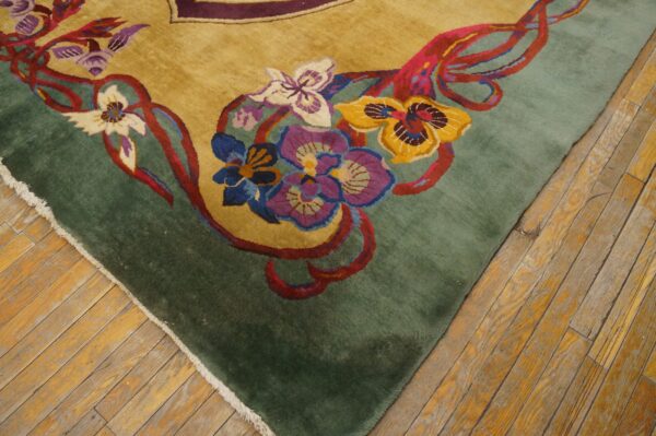 A high-pile rug with colorful floral motifs on a gold and green field rests on distressed wooden floors.