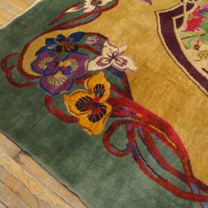 Close-up showing a high-pile floral rug with gold and green fields resting on worn hardwood.