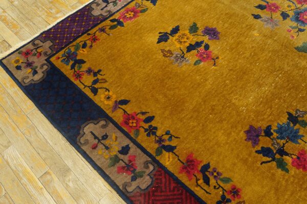 Mustard yellow rug featuring multicolored floral sprays and layered navy, purple, and brown borders on wood flooring.