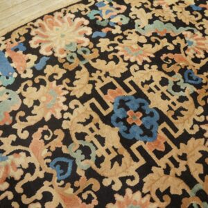 Rounded rug featuring tan, coral, blue, and green floral patterns on a dark ground, on wood flooring.