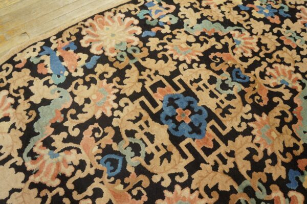 Rounded rug featuring tan, coral, blue, and green floral patterns on a dark ground, on wood flooring.