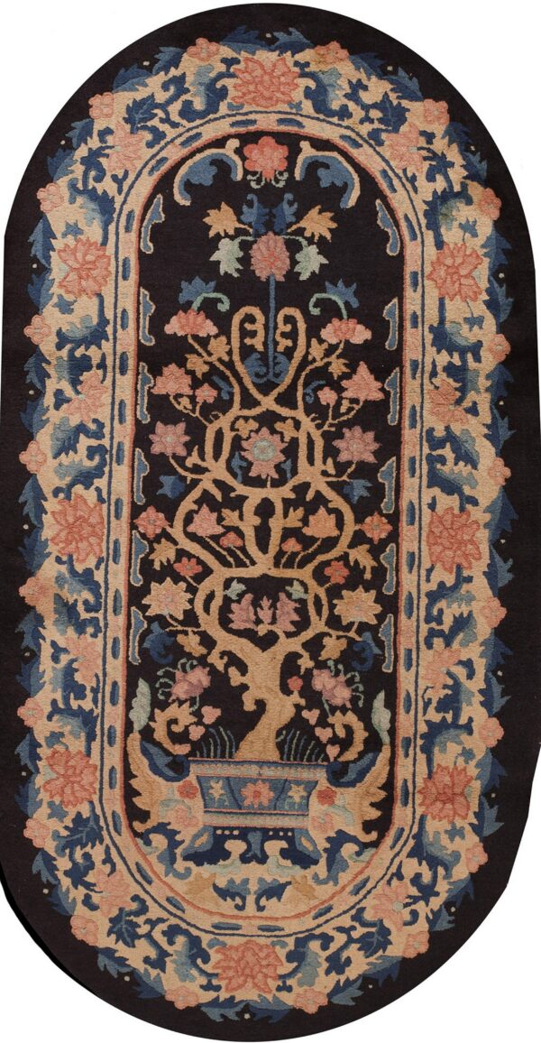 Dark oval rug with a central tree motif and wide floral borders in tan, blue, and salmon.
