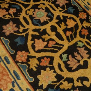 The rug features an intricate floral vine design in gold, coral, and blue on a textured black background.