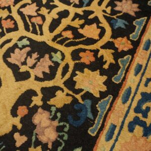 Ornate gold vine pattern with pink, blue, and rust flowers on a contrasting black rug field.