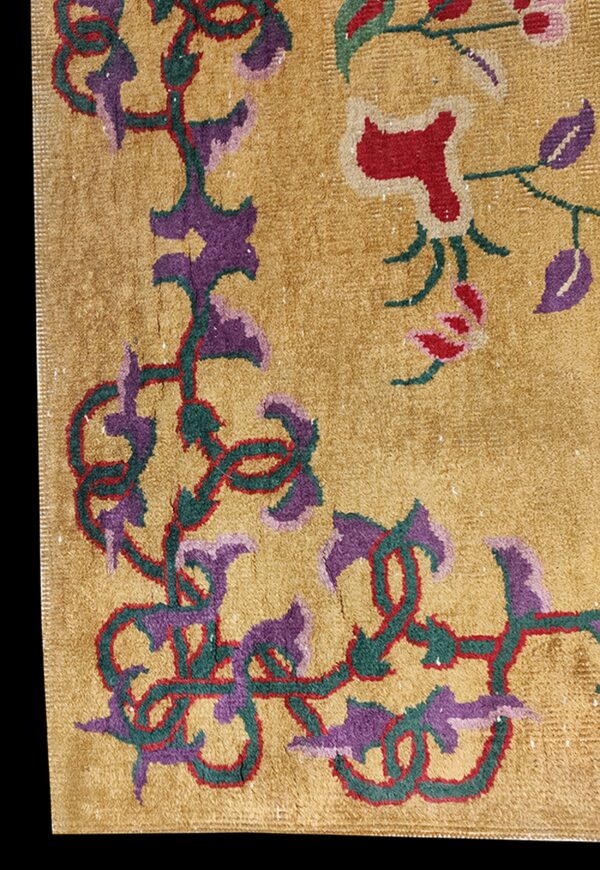 Textured gold rug detail with deep pile and bold purple, red, and green floral designs.