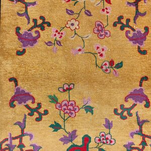 Gold rug with medium pile, decorated with purple, red, and green stylized floral and vine patterns.