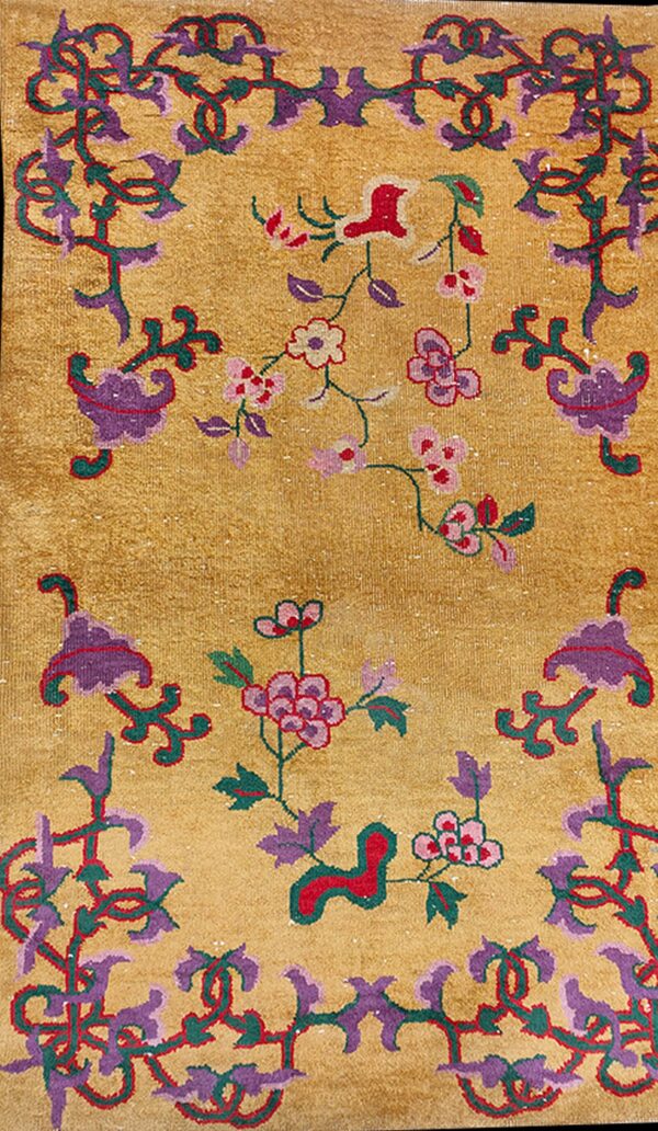Gold rug with medium pile, decorated with purple, red, and green stylized floral and vine patterns.