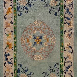 Light blue-green rug with an elaborate central medallion and borders featuring multicolored floral and vine motifs.