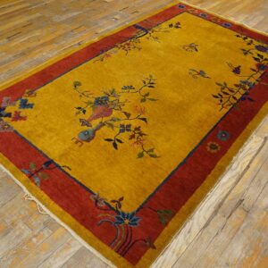 Mustard yellow rug features a red border and blue floral vase pattern on distressed wood floors.