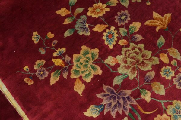Plush red rug featuring a scattered multicolored floral pattern of yellow, green, and purple blooms.