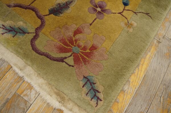 Plush floral rug in yellow and green with red, blue, and purple motifs on distressed wooden flooring.