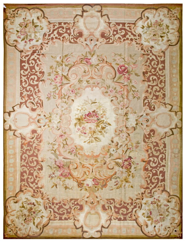 Ornate floral rug displaying a low pile, beige ground, dusty rose scrolling, and faded pink accents.