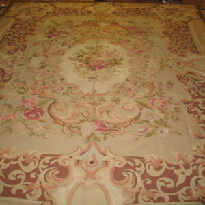 Ornate low-pile rug with a central floral medallion and dusty rose borders laid across wooden floorboards.