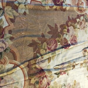 Detailed view of a flat-woven rug with large floral motifs in mauve, cream, olive, and brown.