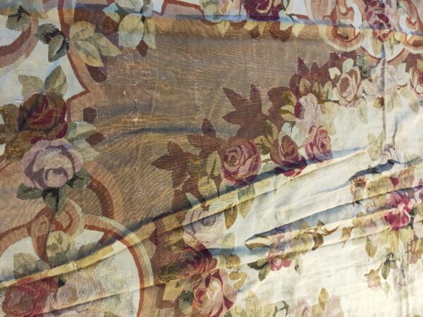 Detailed view of a flat-woven rug with large floral motifs in mauve, cream, olive, and brown.