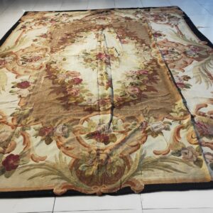 A large, ornate flatwoven rug displays gold and red floral motifs on a cream ground over white tiled flooring.