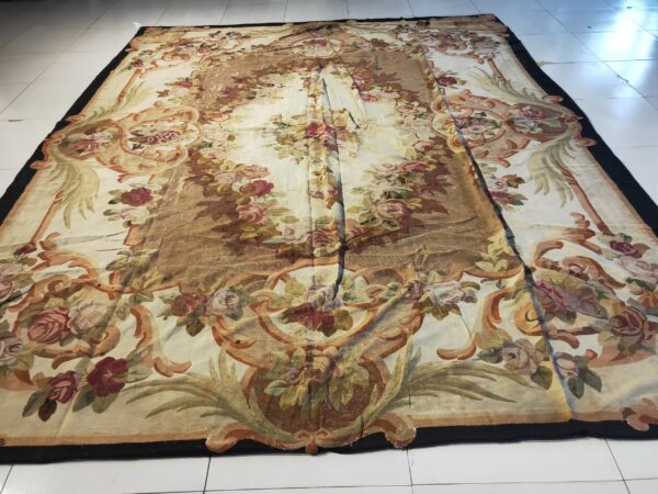 A large, ornate flatwoven rug displays gold and red floral motifs on a cream ground over white tiled flooring.