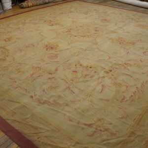 Oversized beige rug featuring an elaborate, muted pink and gold floral design laid on wood flooring.
