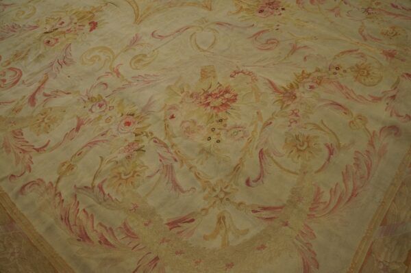 Creamy yellow low-pile rug featuring a dense neoclassical pattern of pink and gold floral motifs.