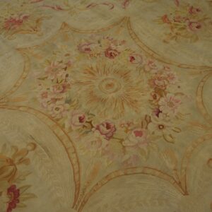 Muted, low-pile rug displaying an ornate floral star medallion pattern in soft pinks and pale gold.