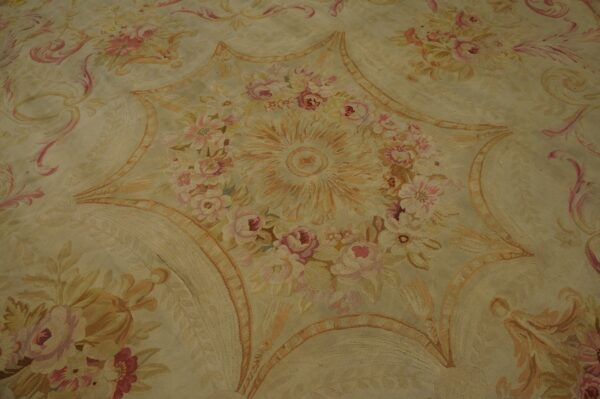 Muted, low-pile rug displaying an ornate floral star medallion pattern in soft pinks and pale gold.