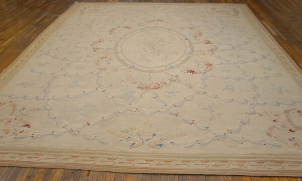 Cream area rug featuring a delicate pink and blue floral trellis pattern surrounding a central bouquet.