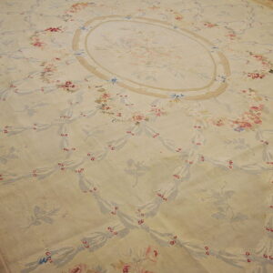Low-pile cream rug with an ornate pale blue and pink floral trellis pattern on wood flooring.