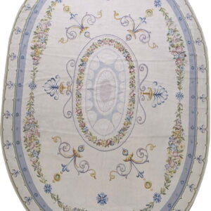 Oval cream rug with pale blue borders and intricate garlands of pink, yellow, and lavender flowers.