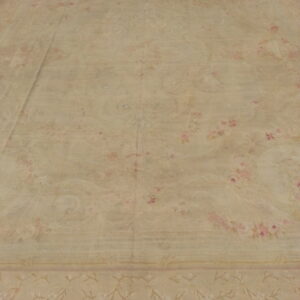 Large pale beige area rug featuring faded pink and cream floral designs on a concrete floor.