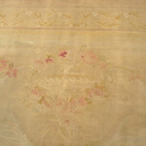Woven rug surface in beige and tan with faded pink rose bouquets and delicate borders.