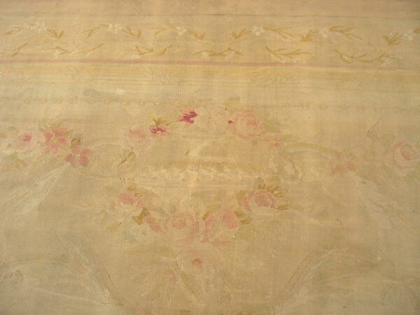 Woven rug surface in beige and tan with faded pink rose bouquets and delicate borders.