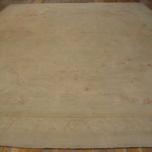 A large pale beige rug with a faint pink and tan floral design lies on hardwood flooring.