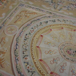 A large rug with an intricate beige, pink, and ivory floral medallion and border design.