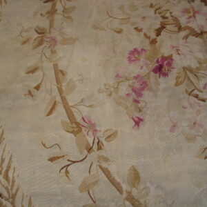 A detailed view of a cream flatweave rug displaying a faded pink and tan botanical design.