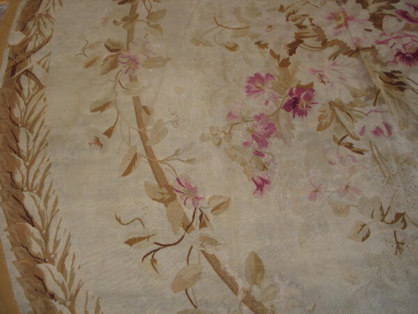 A detailed view of a cream flatweave rug displaying a faded pink and tan botanical design.