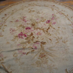 Round cream and pink floral rug featuring large roses and vine patterns on light hardwood flooring.