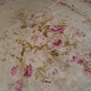 Muted floral rug with rose and magenta blossoms against a low-pile cream and tan woven background.
