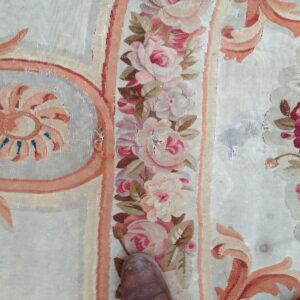 Close-up of a floral flatweave rug showing pink roses, peach scrolls, and a pale neutral background with a brown shoe toe.