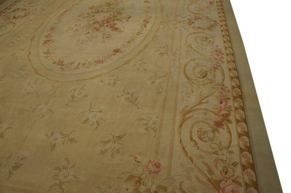 Detail of a pale gold rug showing pink roses, white floral sprigs, and tan neoclassical scrollwork.