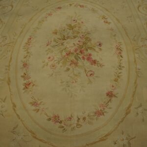 Pale yellow rug features an oval floral medallion of pink roses and scrolling leaf motifs.