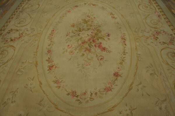 Pale yellow rug features an oval floral medallion of pink roses and scrolling leaf motifs.