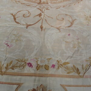 Low-pile rug detail showing large scrolling foliage, tan vines, and magenta roses on an ivory background.